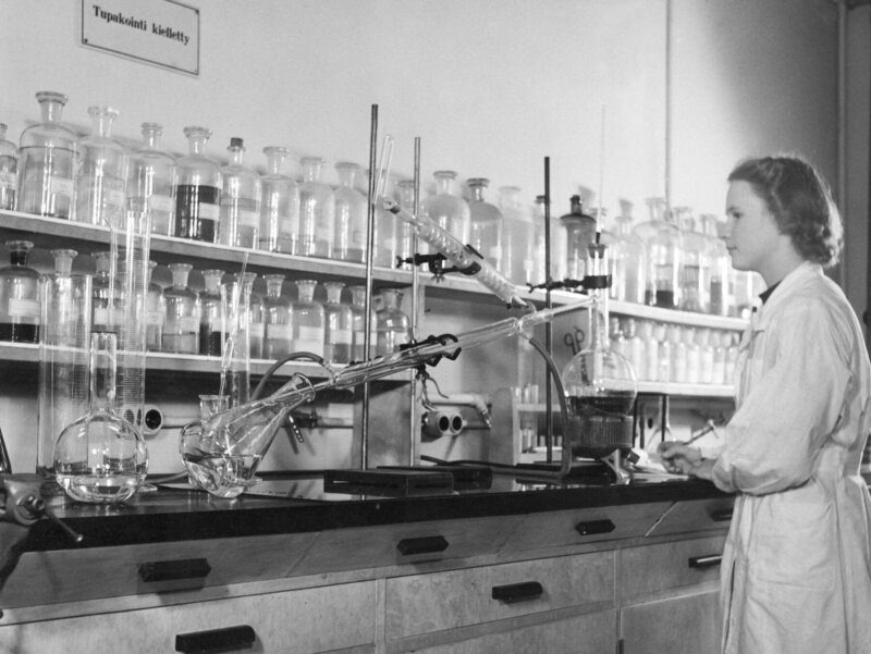 Kuvassa on 1950-1960-luvulla nainen tekemässä laadunvalvontaa laboratoriossa.