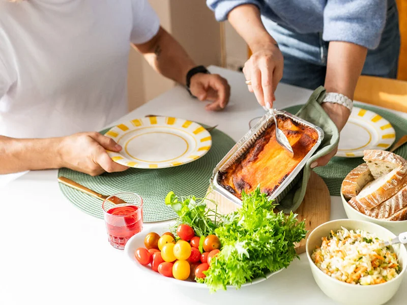 Pariskunta ottamassa ruokapöydän ääressä ruokaa
