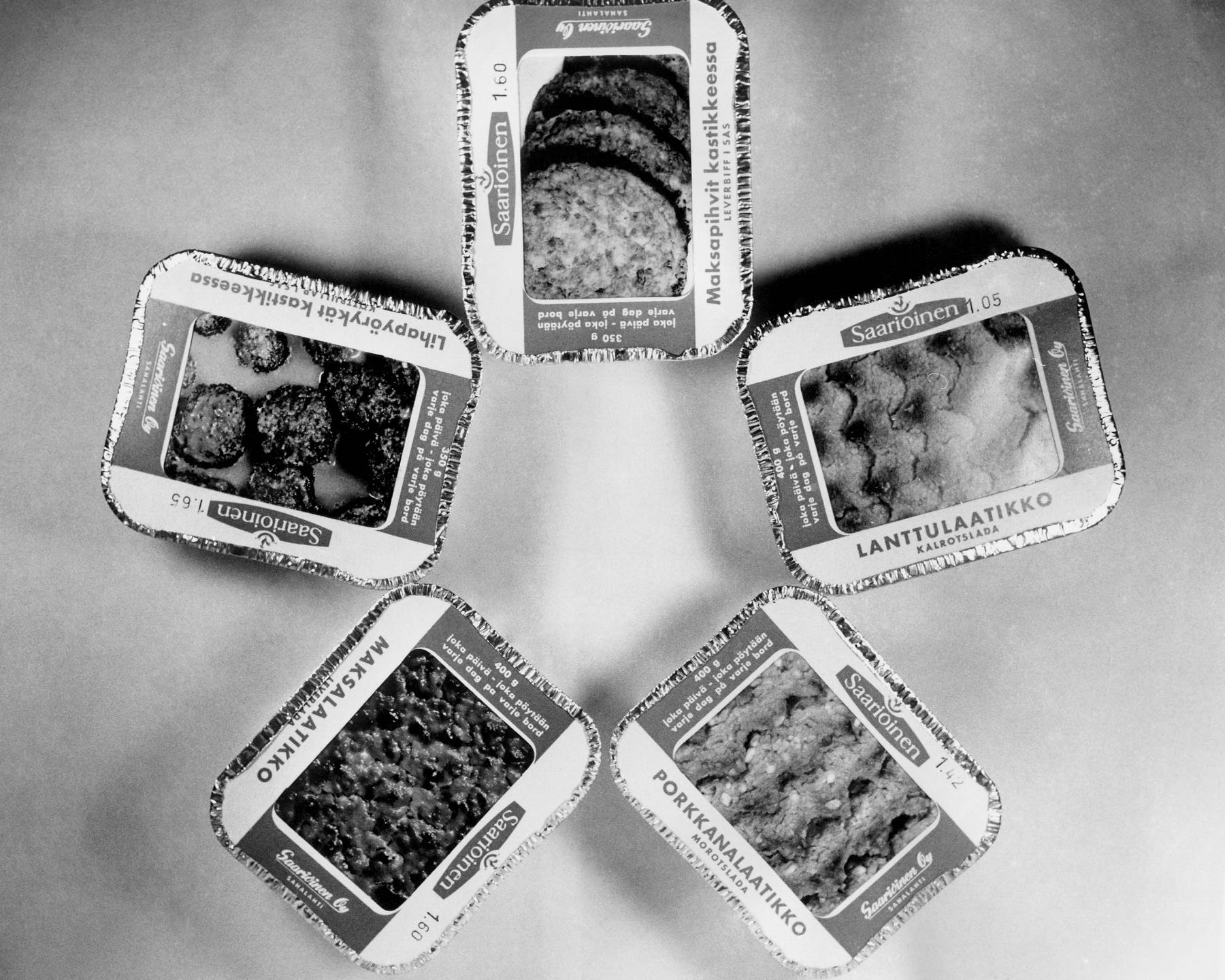 Kuvassa on Saarioisten laatikoita 1950-luvulta: maksalaatikko, lanttulaatikko, lihapyörykät kastikkeessa, porkkanalaatikko ja maksapihvit kastikkeessa.