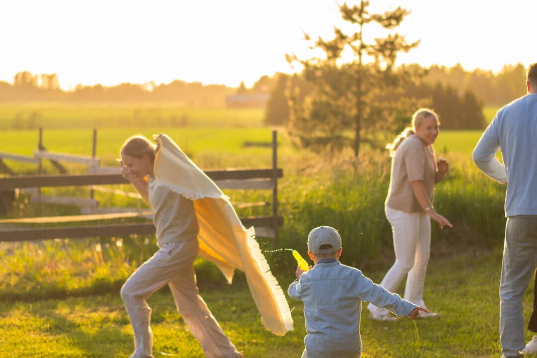Kuvassa on perhe kesällä pelaamassa vesisotaa.