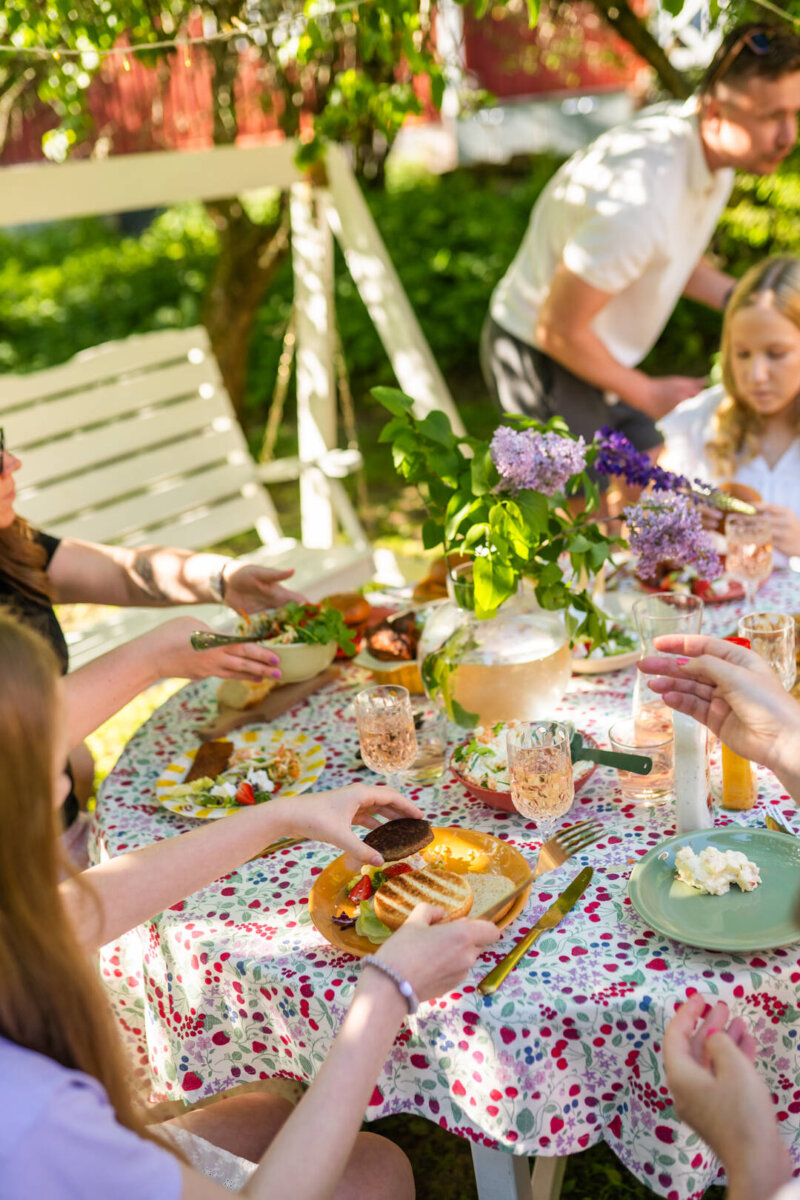 Kuvassa on pihalla ruokapöytä täynnä burgereita ja niiden lisukkeita.