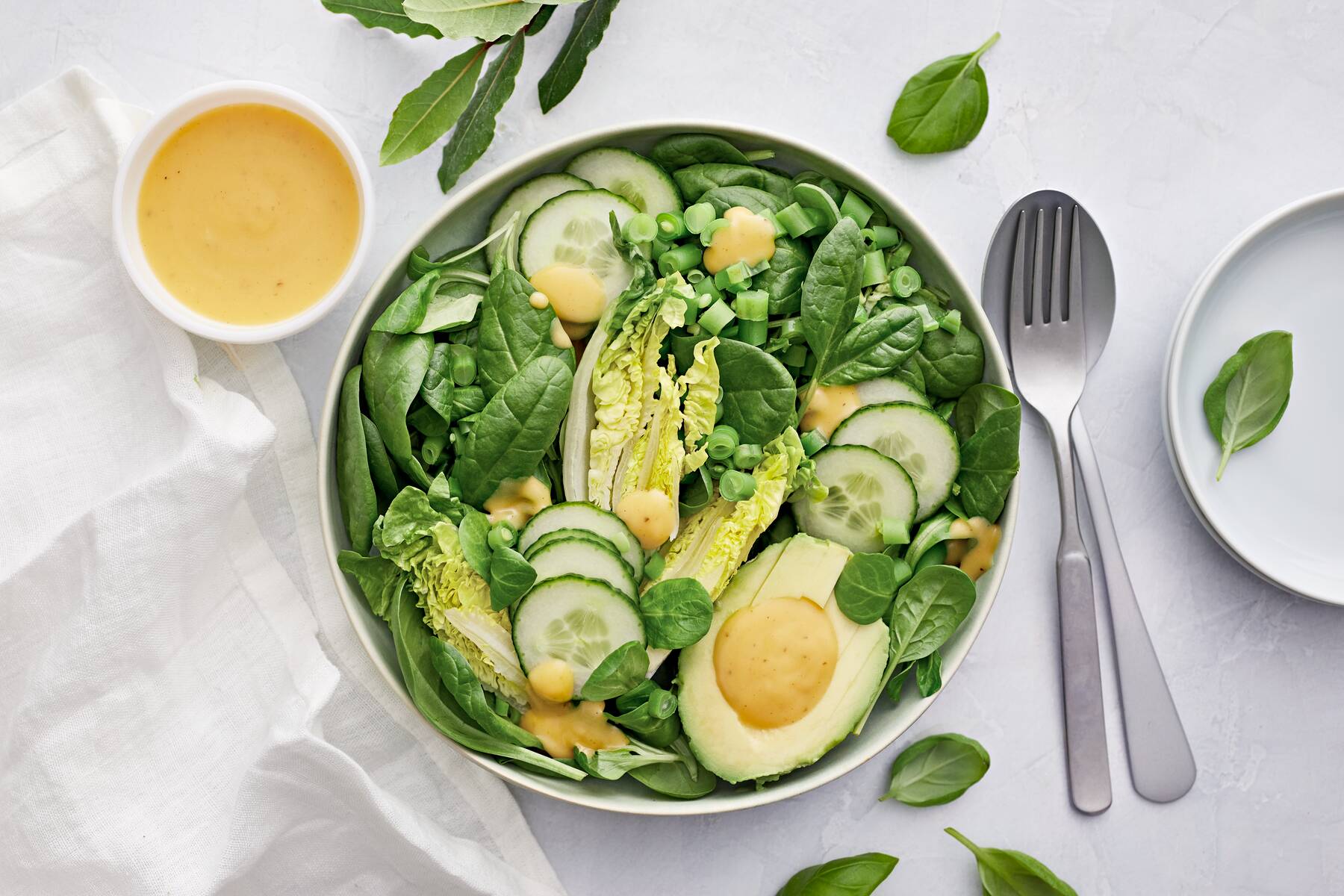 Kuvassa on vihreää salaattia ja salaattikastiketta