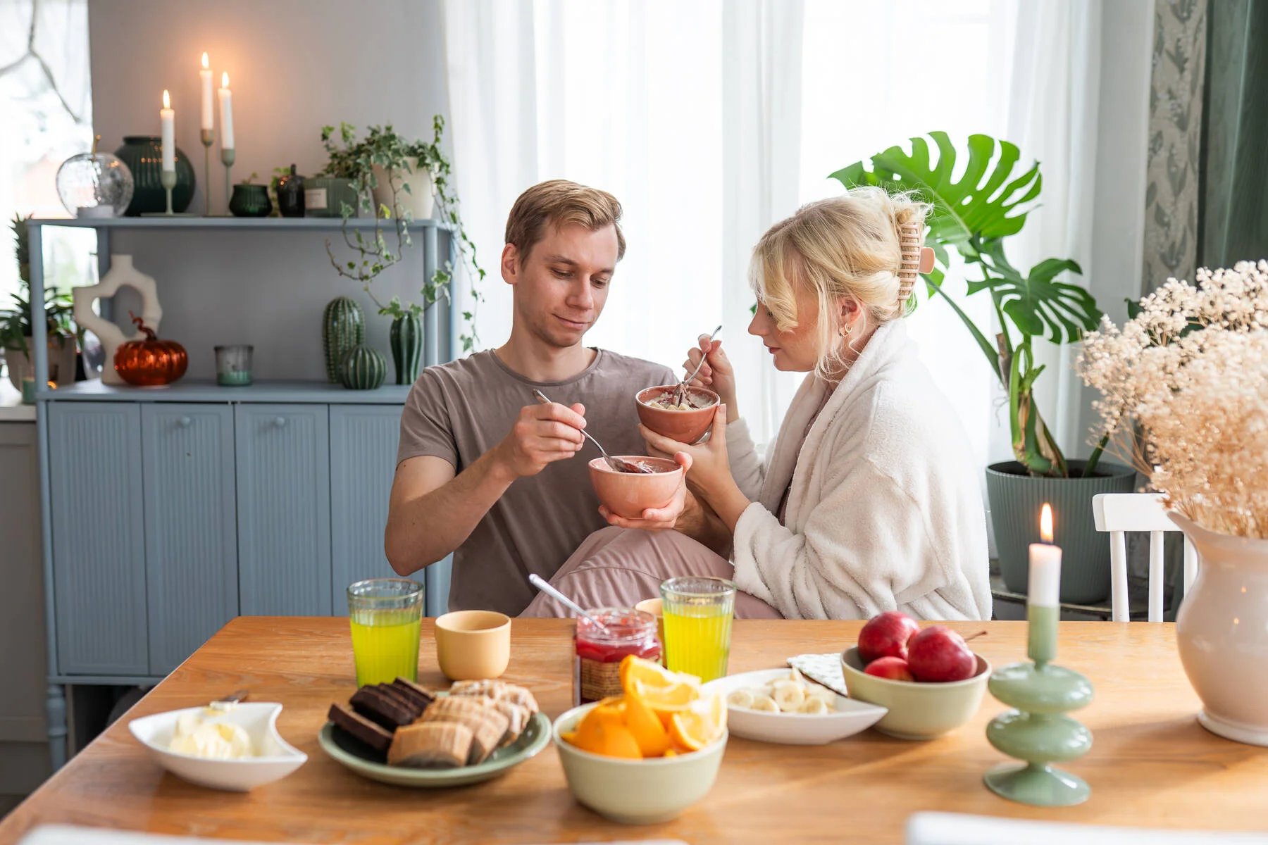 Kuvassa on kaksi henkilöä ruokapöydän ääressä, jolle on koottu brunssi.