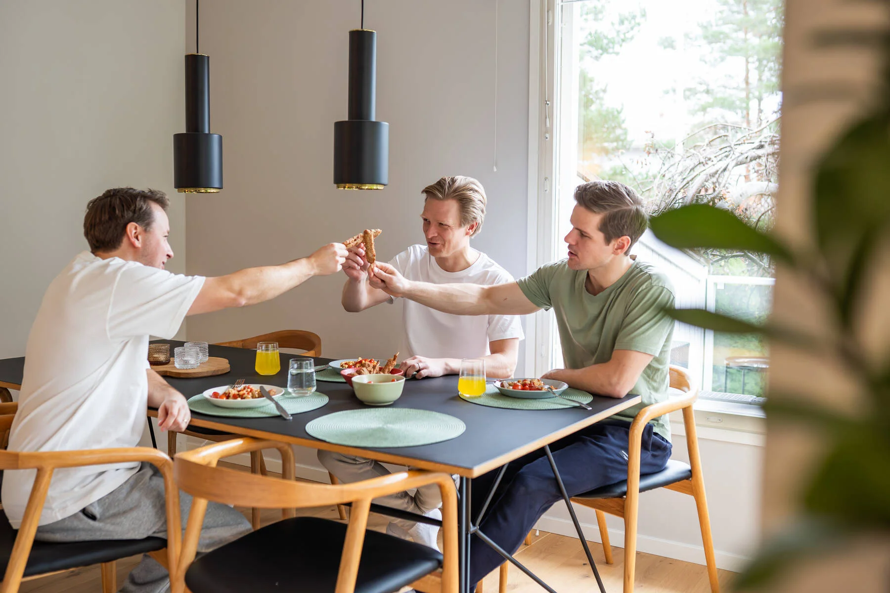 Kuvassa on kolme henkilä ruokapöydän ääressä.