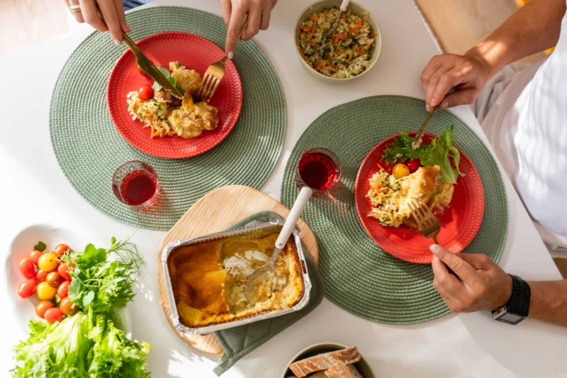 Ruokailuhetki, pöydässä kaksi lautasta ja vuokaruokaa
