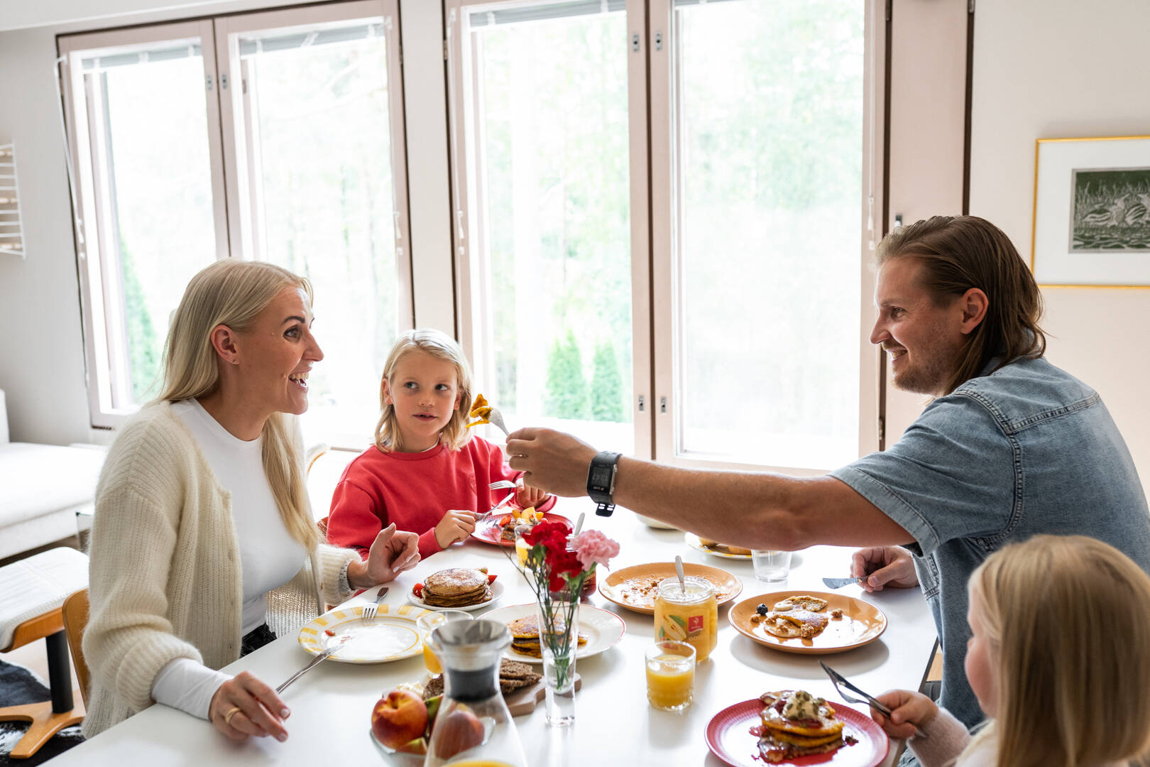 Kuvassa on perhe ruokapöydän ääressä syömässä rahkalettuja.