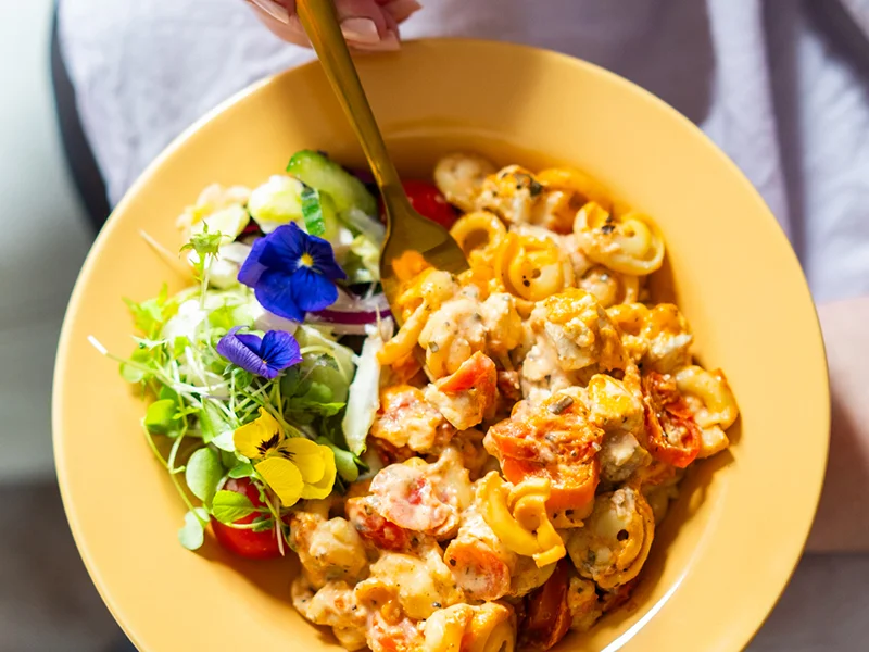 Kuvassa on lautasella tomaatti-fetapastaa ja salaattia.