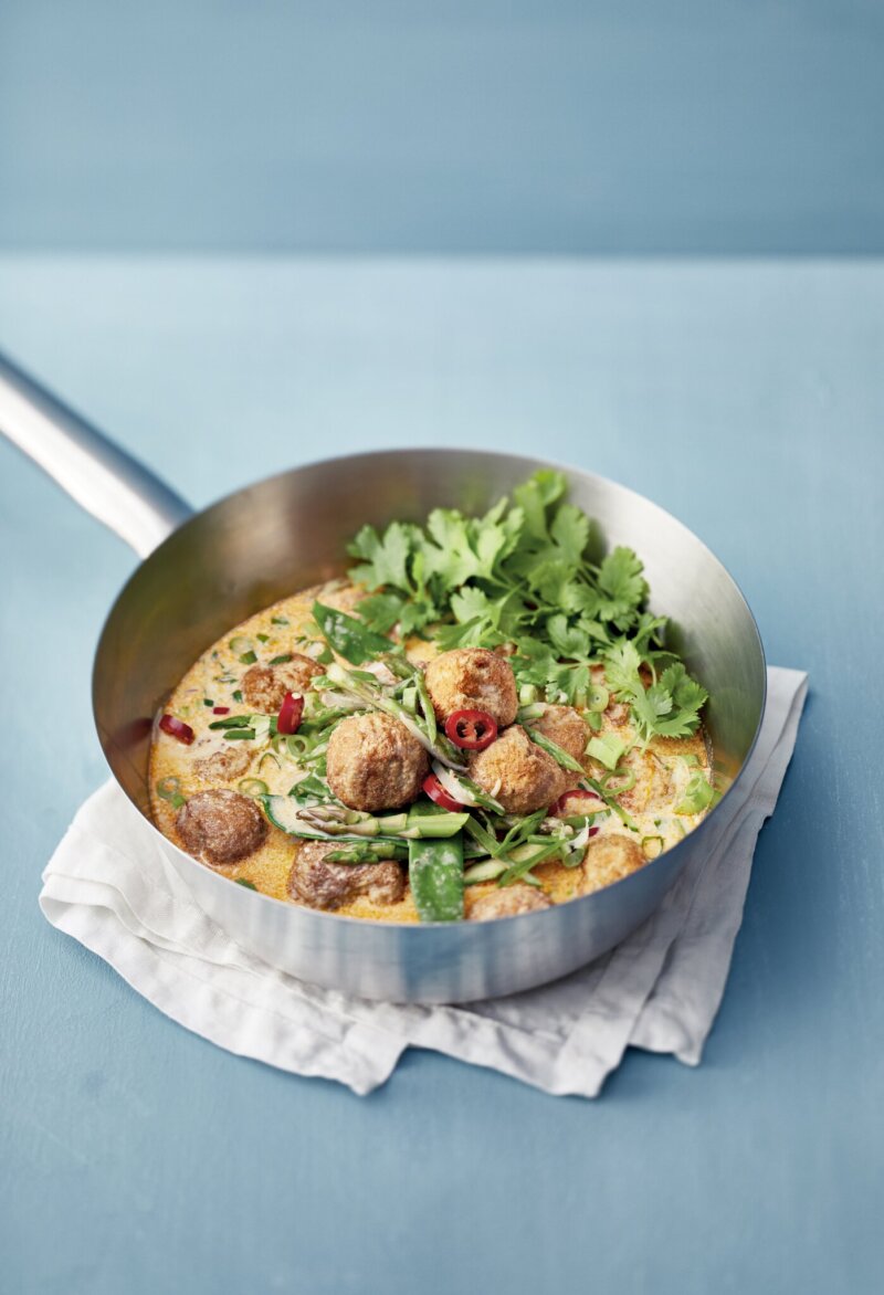 Kalapyöryköitä punaisessa currykastikkeessa, sekä paljon tuoreita yrttejä.