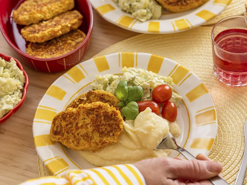 Lautasella muusia, kasvispihvejä ja tomaatteja.